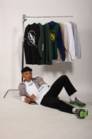 Man sitting on the floor with a rack of clothes behind him