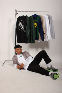 Man sitting on the floor with a rack of clothes behind him